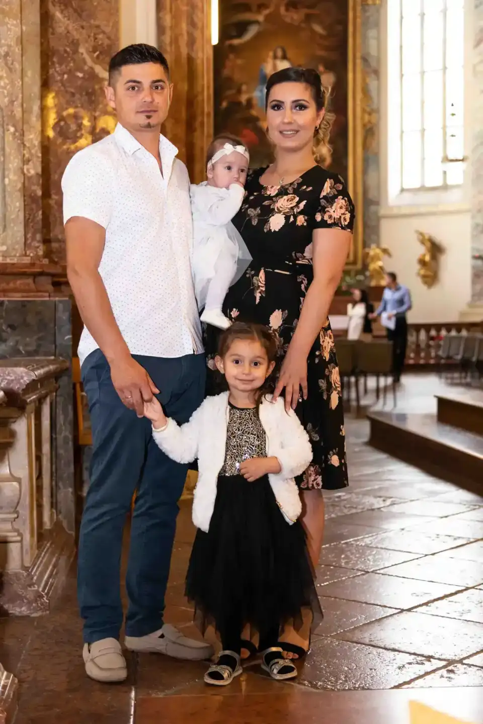 Familie mit zwei Kindern in einer Kirche während einer Taufe, professionelle Eventfotografie Wien