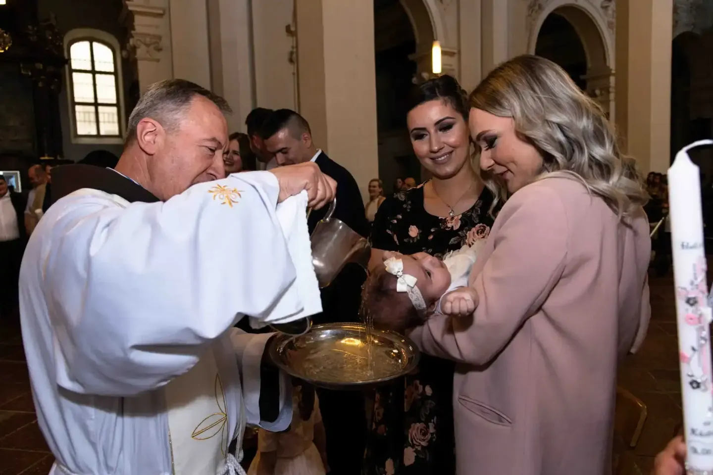 Priester segnet Neugeborenes bei Taufe in Wien-Kirche, Eventfotograf dokumentiert Moment mit Familie