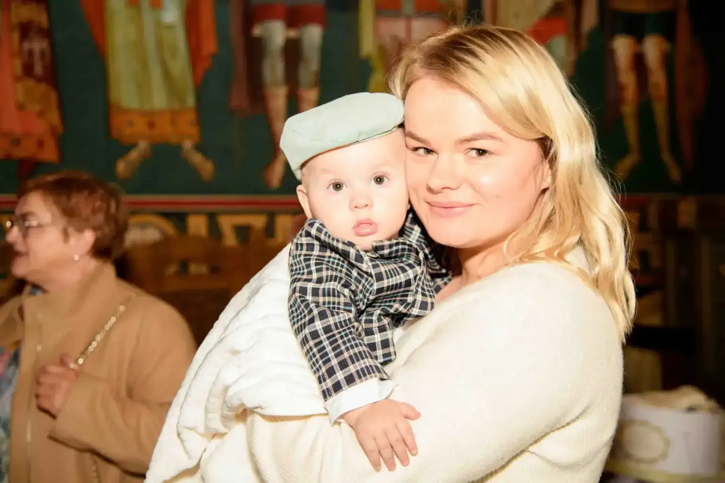 Mutter hält Neugeborenes bei der Taufe in einer Kirche, Eventfotografie Wien