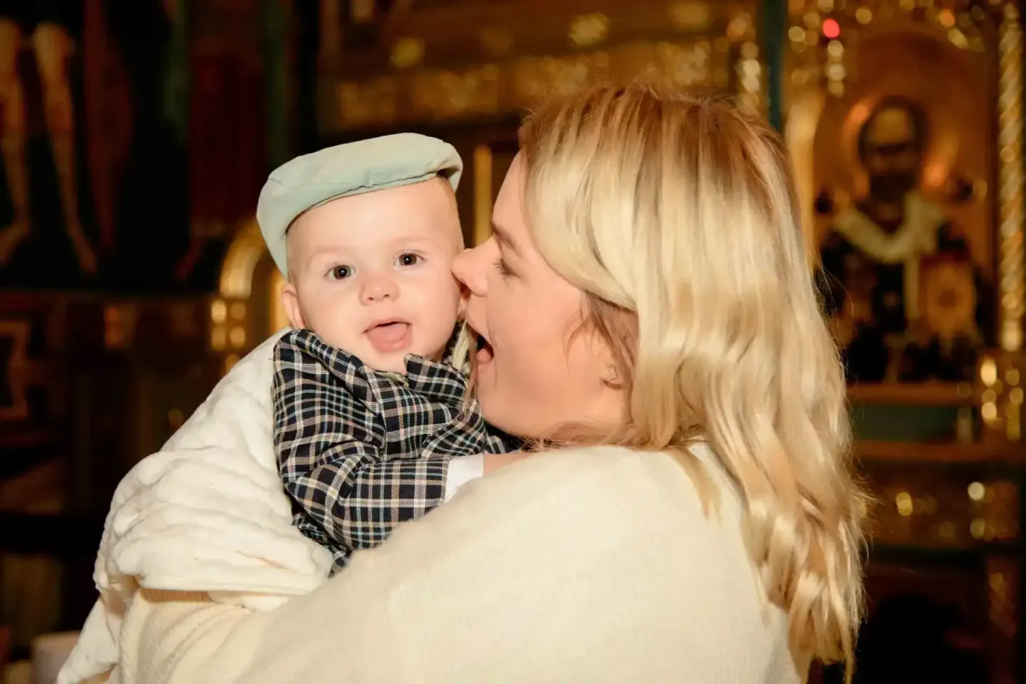 Mutter hält lachendes Baby in Taufkleidung, professionelle Eventfotografie Wien