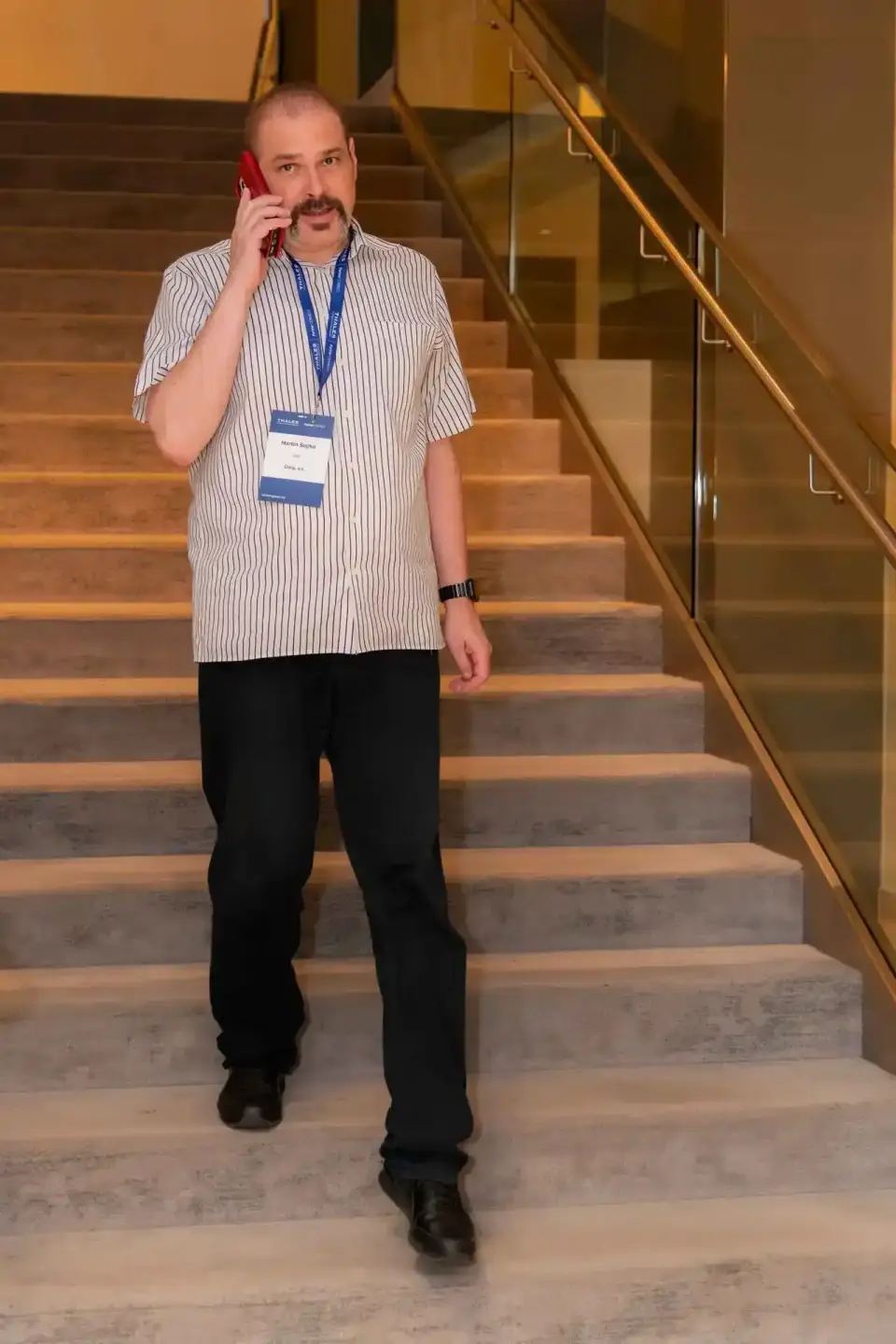 Mann mit Namensschild telefoniert auf Treppe während Firmenevent Wien