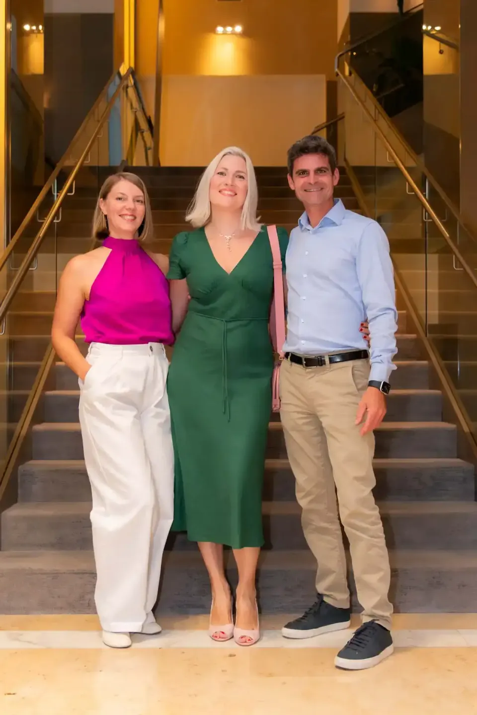 Drei Personen beim Thales Firmenevent in Wien, stehen lächelnd auf einer Treppe bei warmem Licht