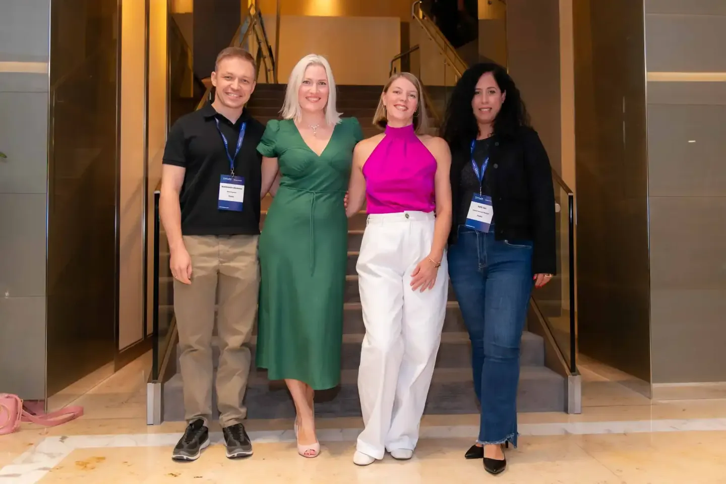 Vier Personen beim Thales Firmenevent in Wien, zwei tragen Badges, gruppiert vor modernem Treppenaufgang