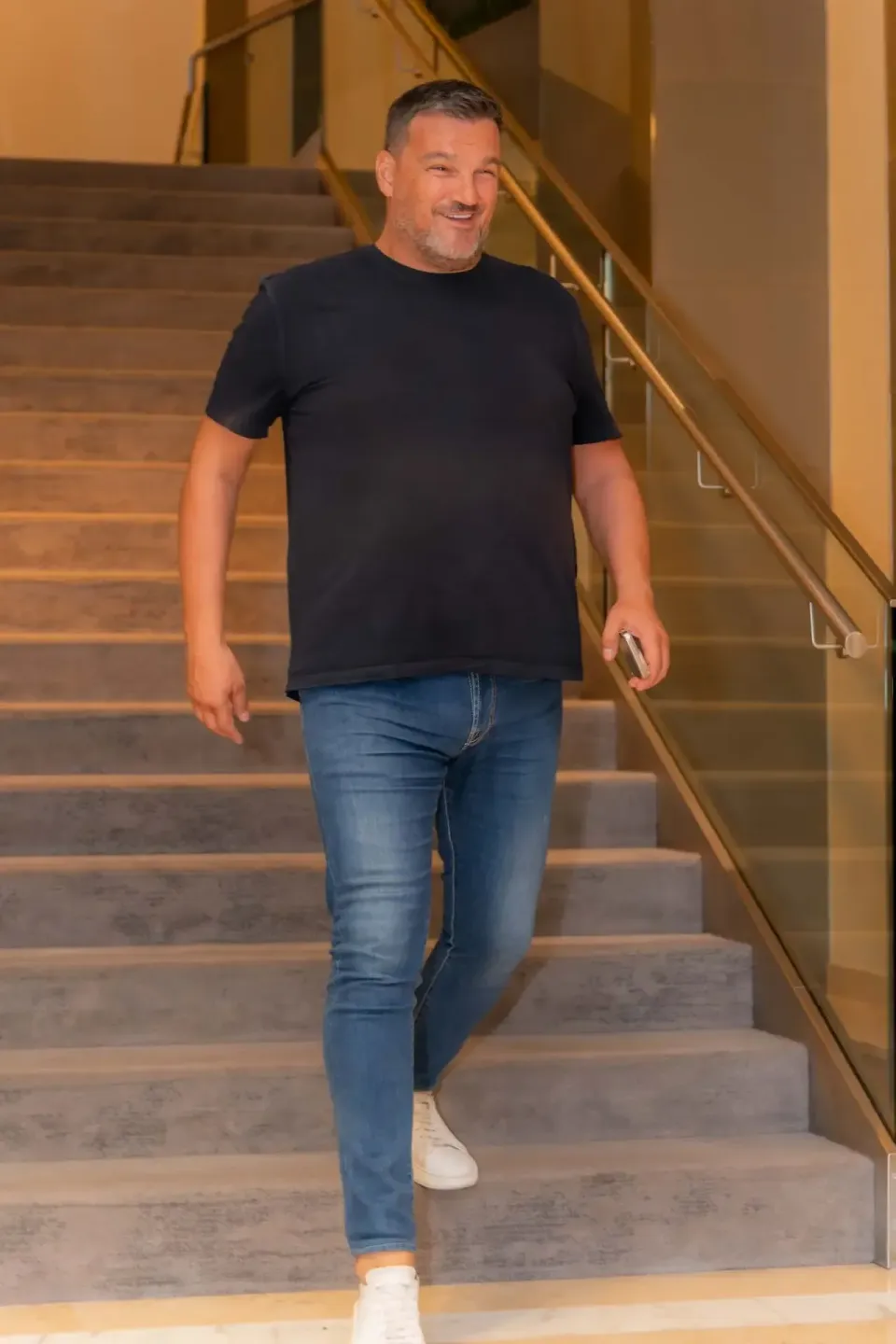 Mann in schwarzem T-Shirt und Jeans läuft die Treppe hinunter bei Eventfotografie Wien