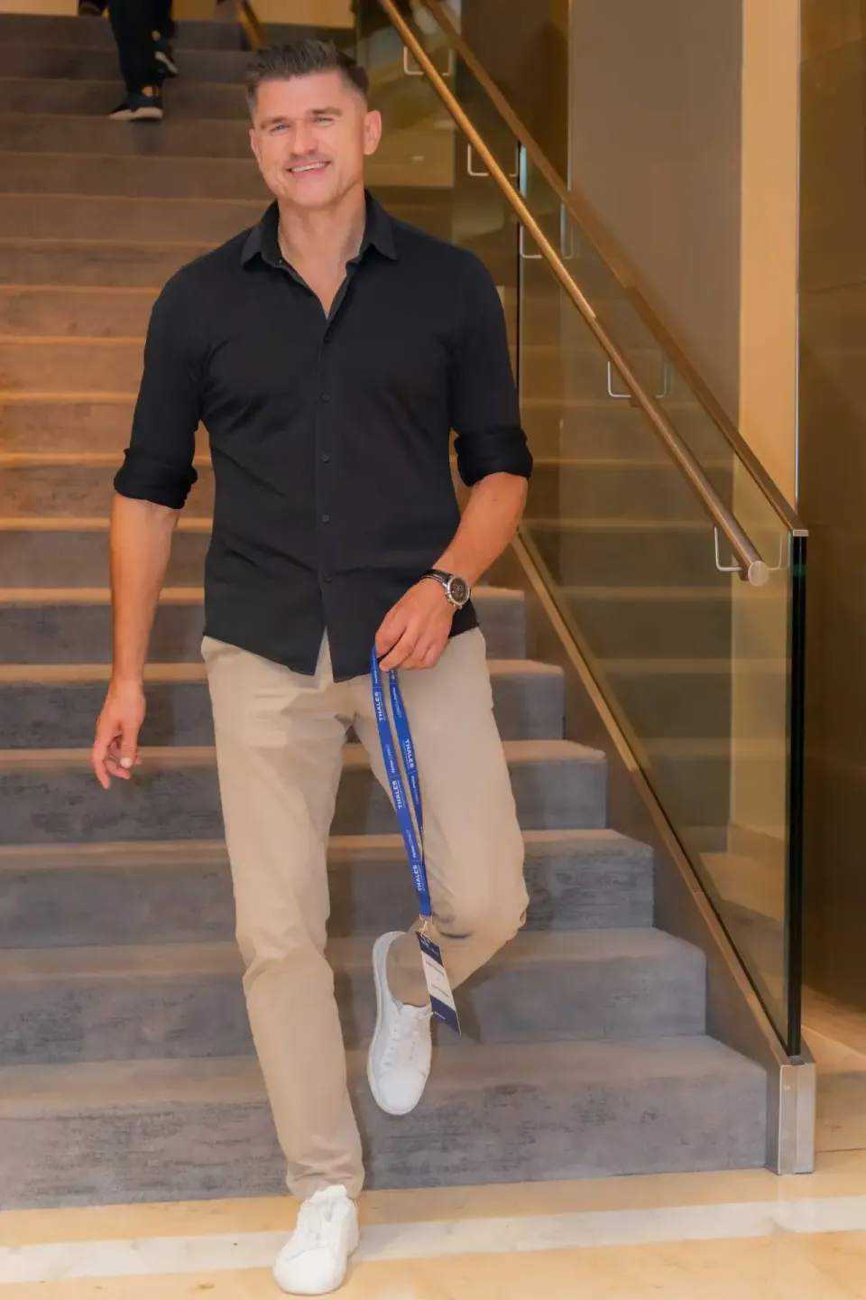 Mann in schwarzem Hemd und beigem Chino auf Treppe beim Thales Firmenevent – professionelle Eventfotografie Wien