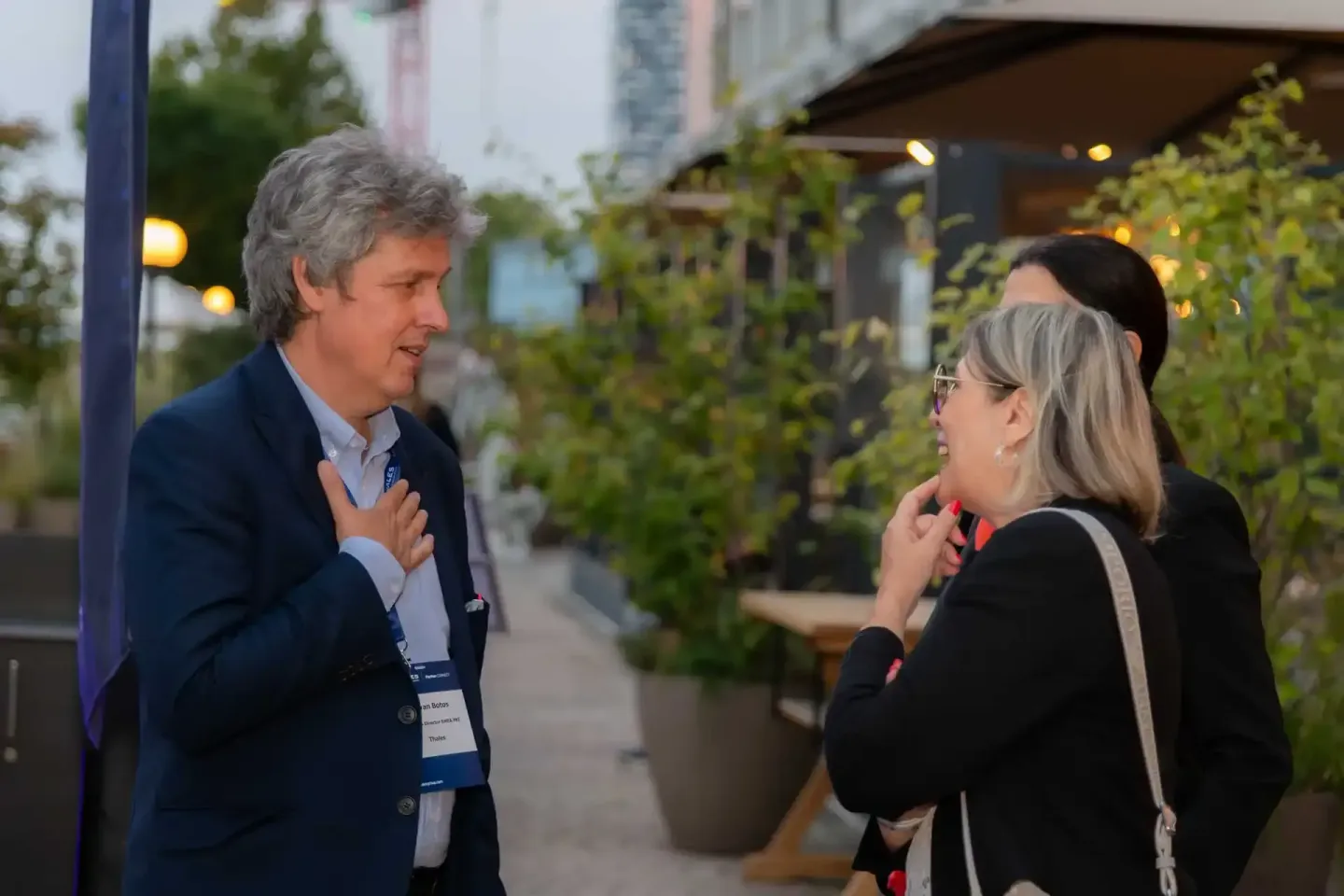 Zwei Personen im Gespräch bei einem Firmenevent Wien, Mann in dunklem Anzug mit Namensschild spricht mit Frau in schwarzer Ja