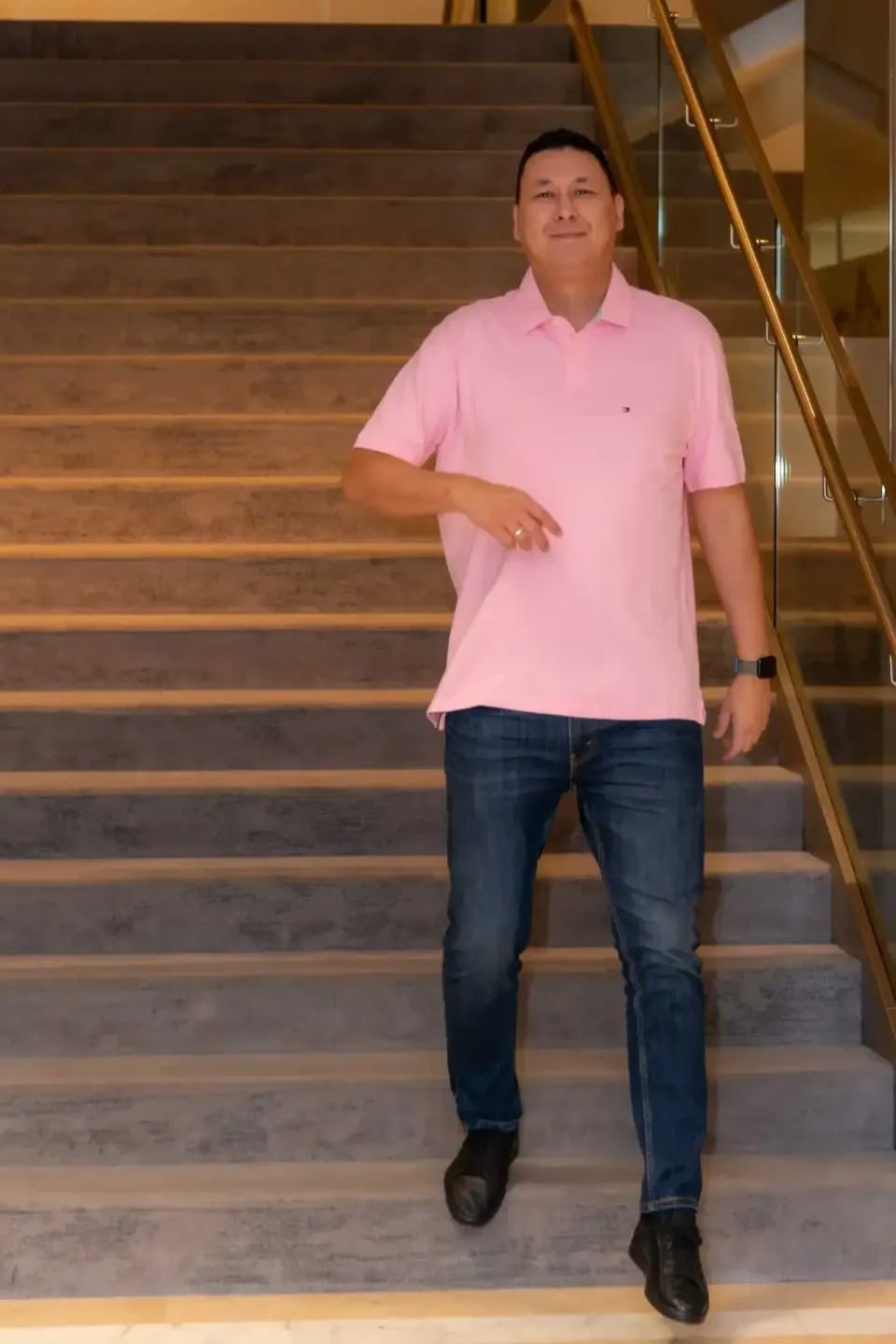 Mann in rosa Poloshirt und Jeans auf Holztreppe, professionelle Eventfotografie Wien