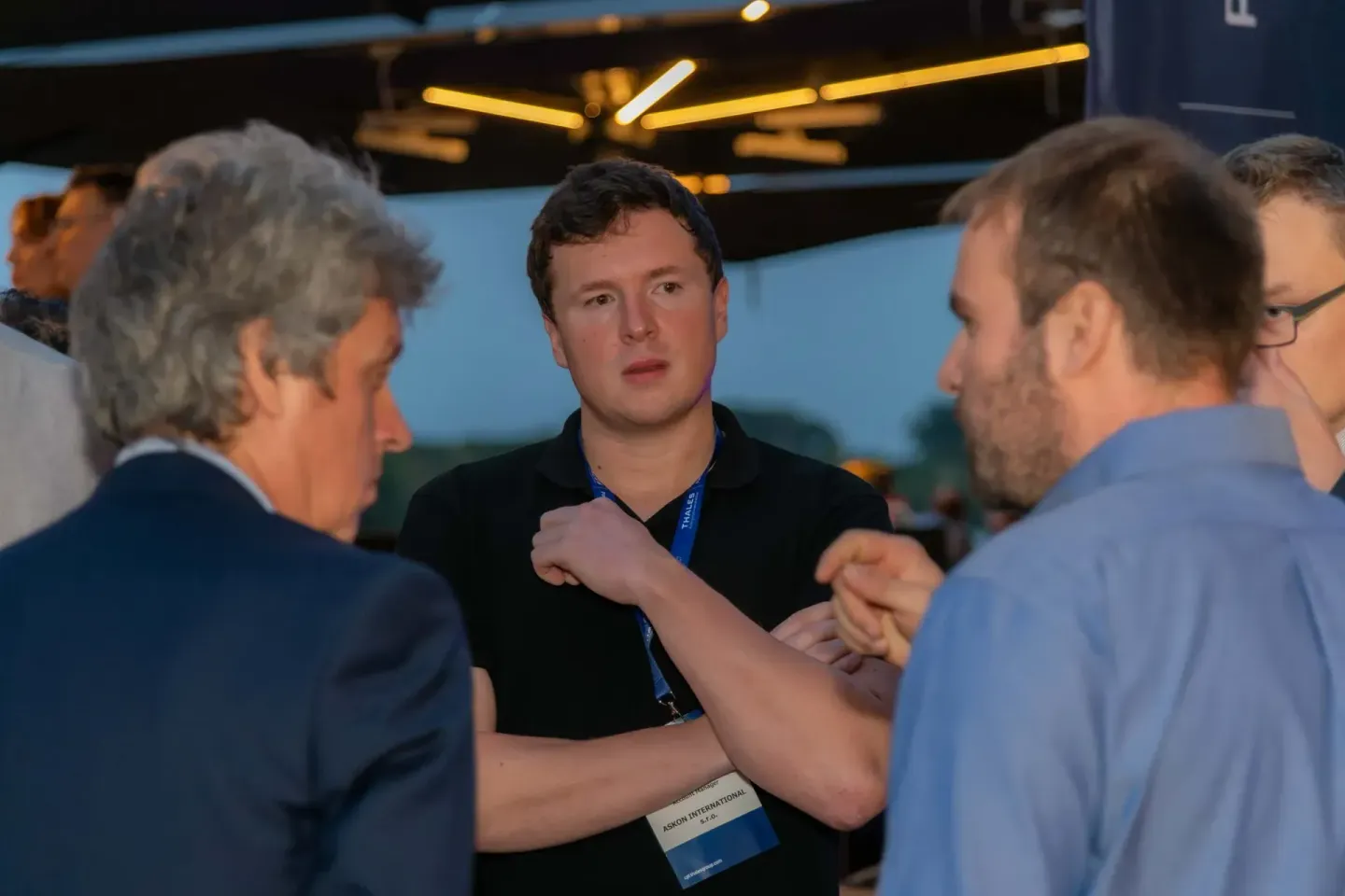 Eventfotograf dokumentiert Geschäftsgespräch zwischen drei Männern auf Thales Firmevent in Wien