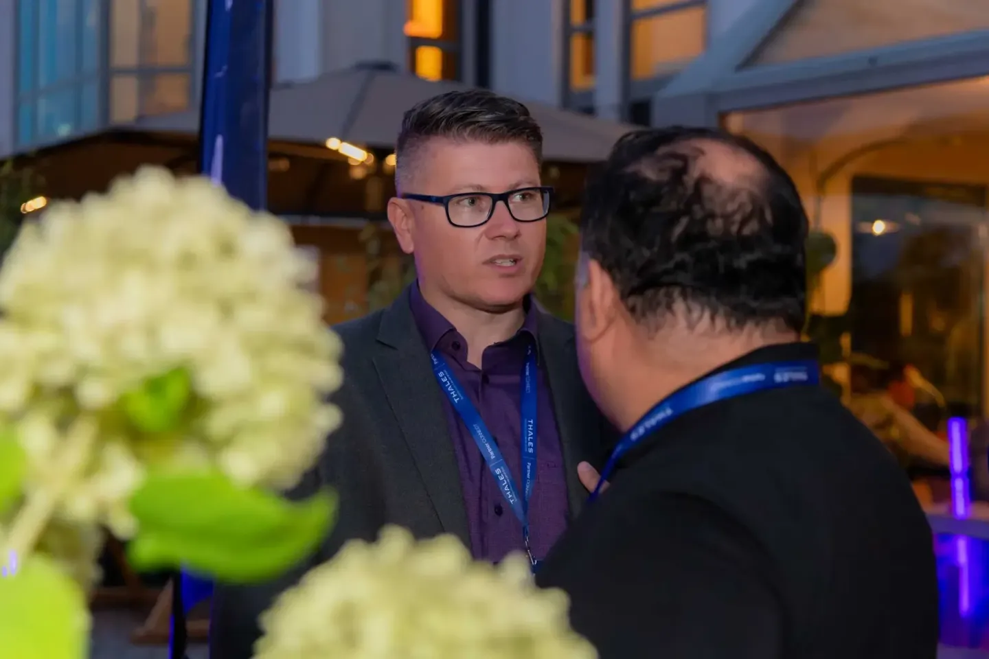 Zwei Personen im Gespräch bei einem Firmenevent in Wien, einer trägt Brille und ein Lanyardausweises