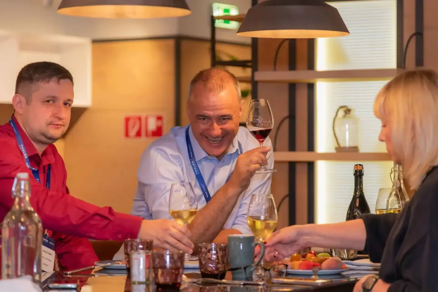 Drei Geschäftsleute stoßen mit Wein an, Eventfotografie Wien bei Thales Firmenevent