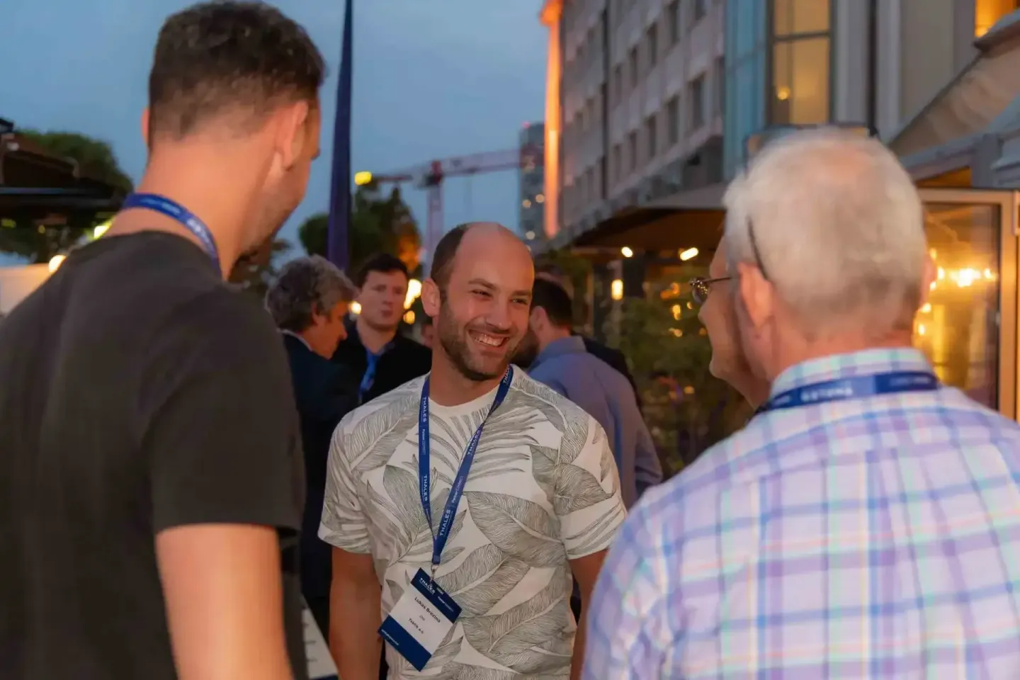 Eventfotograf dokumentiert Networking-Moment bei Thales Firmenevent in Wien mit lachenden Gästen am Abend