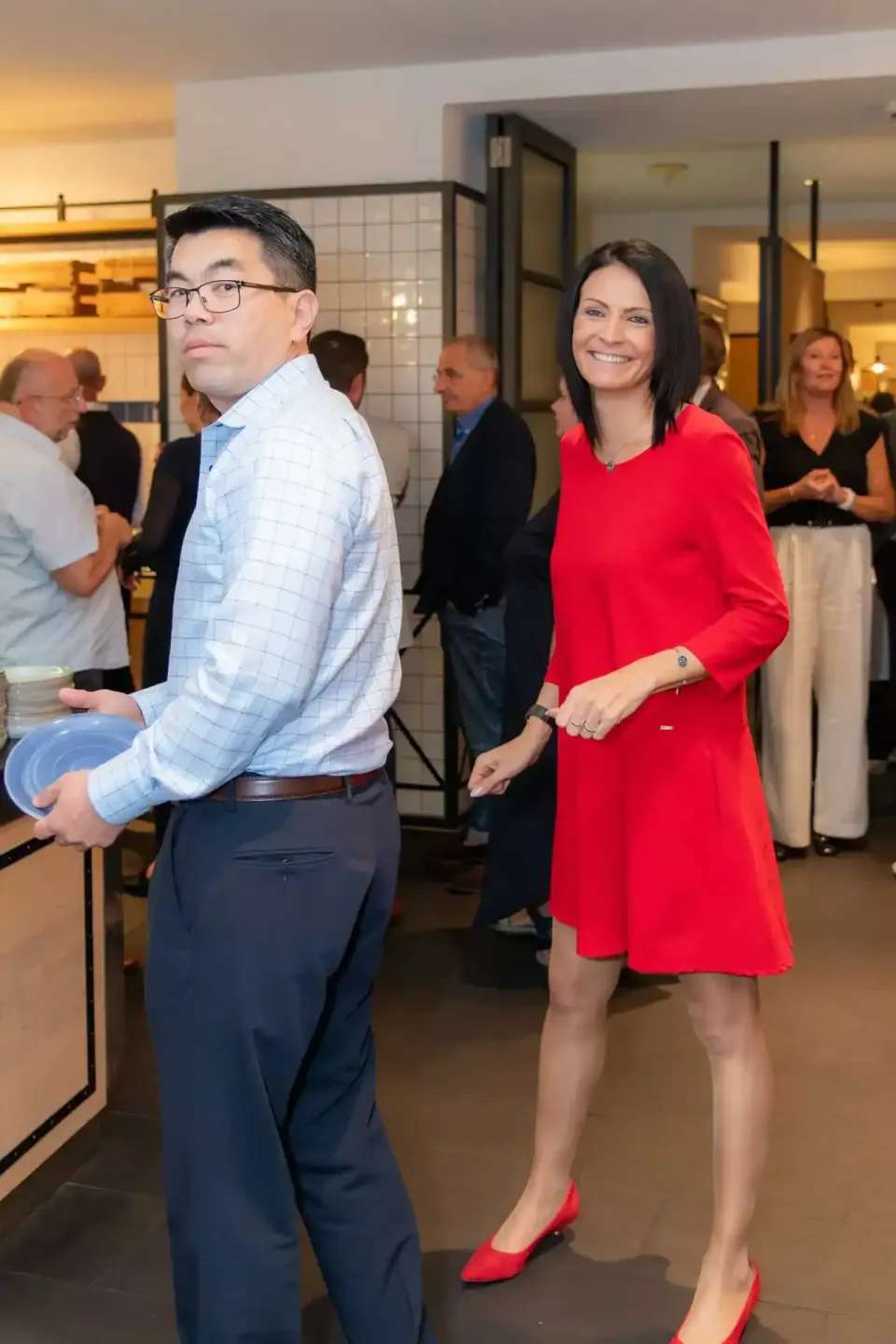 Eventfotografie Wien: Zwei Personen in eleganter Kleidung bei einem Firmenevent, im Hintergrund weitere Gäste in modernem Ver