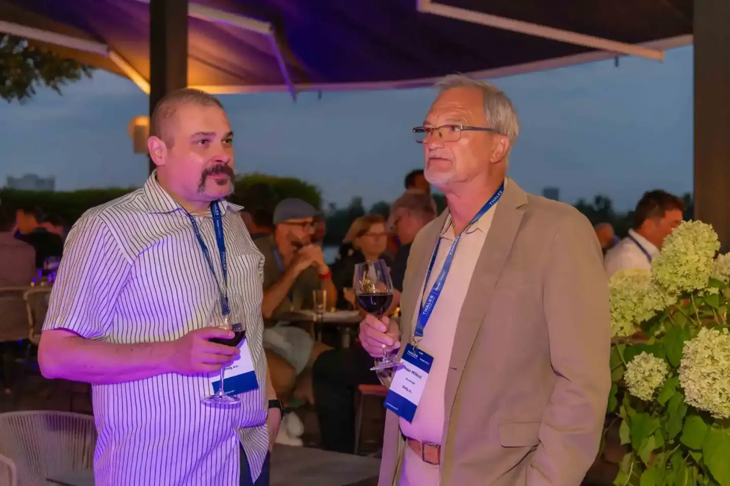 Zwei Geschäftsmänner im Gespräch bei einem Firmenevent Wien mit Getränken und Ausblick