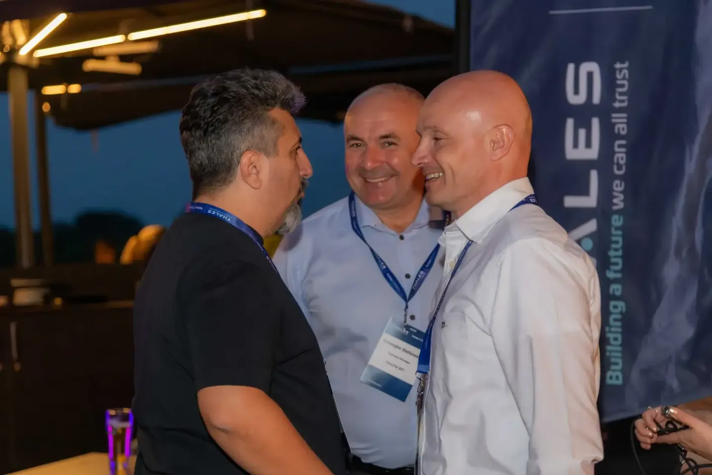 Drei Geschäftsmänner im Gespräch bei einem Firmenevent Wien, zwei tragen Namensschilder