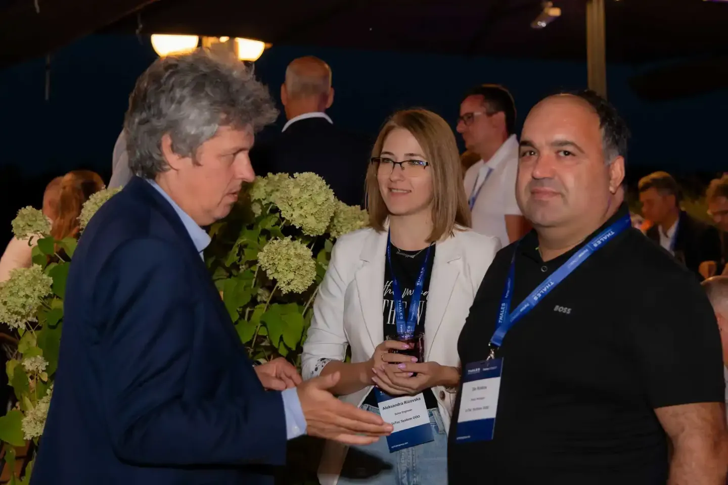 Eventfotograf dokumentiert Networking-Gespräch zwischen drei Personen mit Auszeichnungen bei Thales Firmenevent in Wien