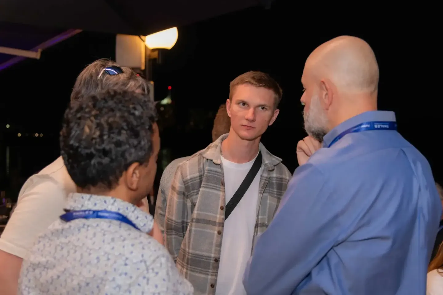 Drei Männer im Dialog bei einem Firmenevent Wien, Networking und Gespräch im Innenraum mit Beleuchtung