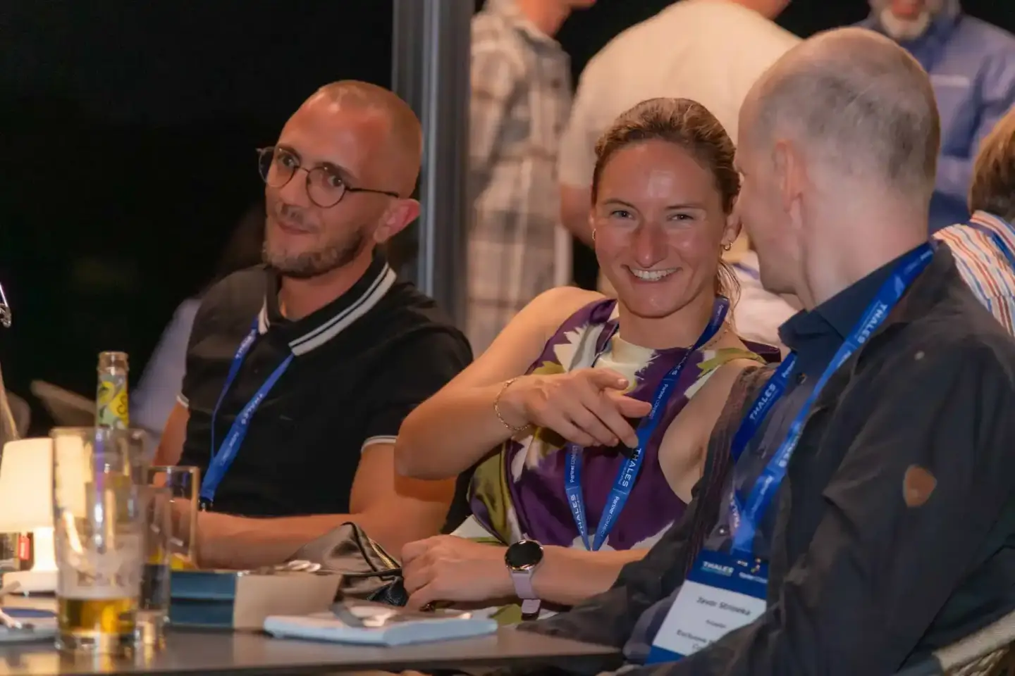 Eventfotografie Wien: Teilnehmer mit Badges diskutieren engagiert an einem Konferenztisch bei der Thales Veranstaltung