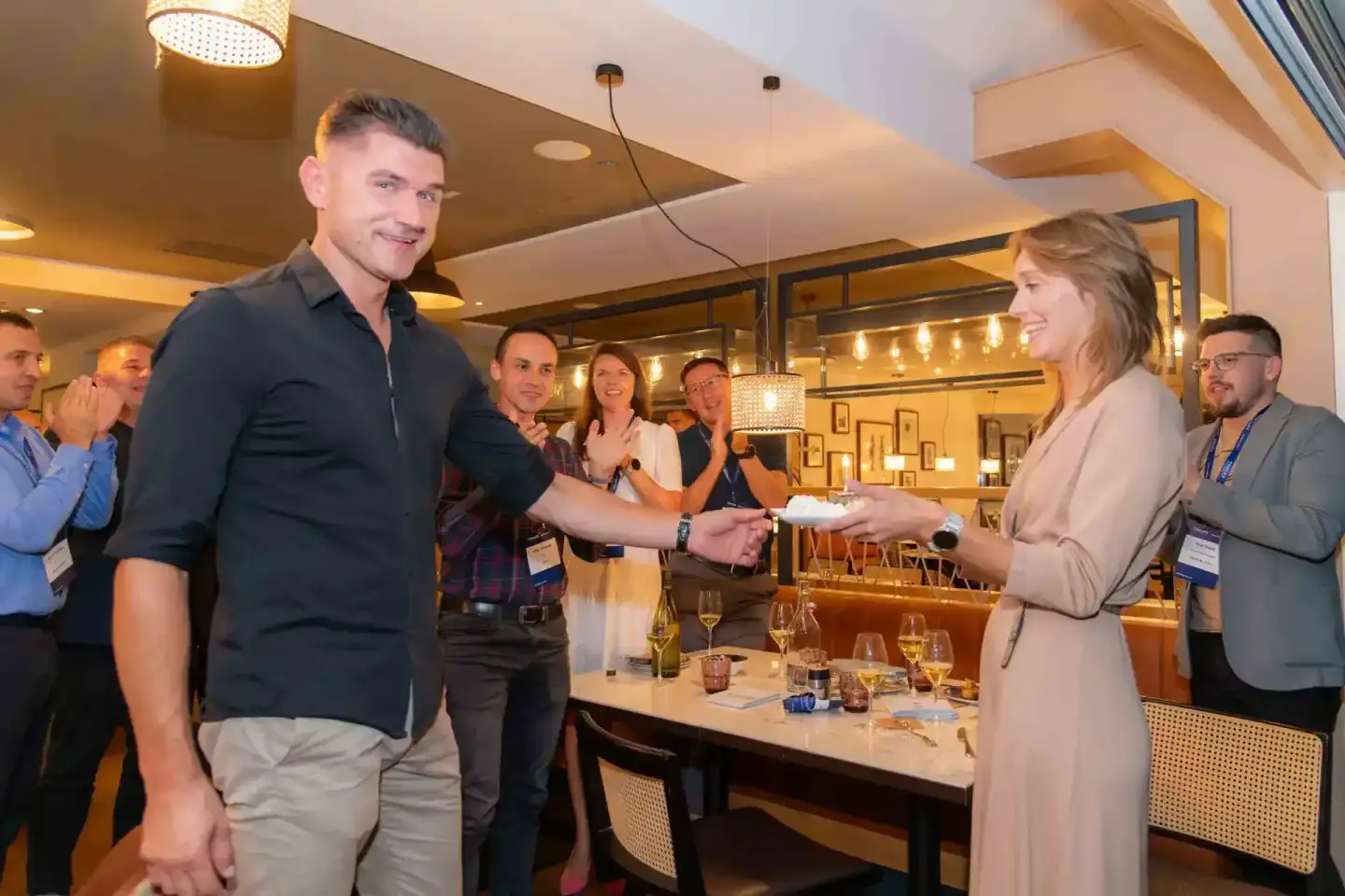 Zwei Personen schütteln sich die Hand auf einem Firmenevent in Wien, umgeben von Gästen in elegantem Restaurant-Setting