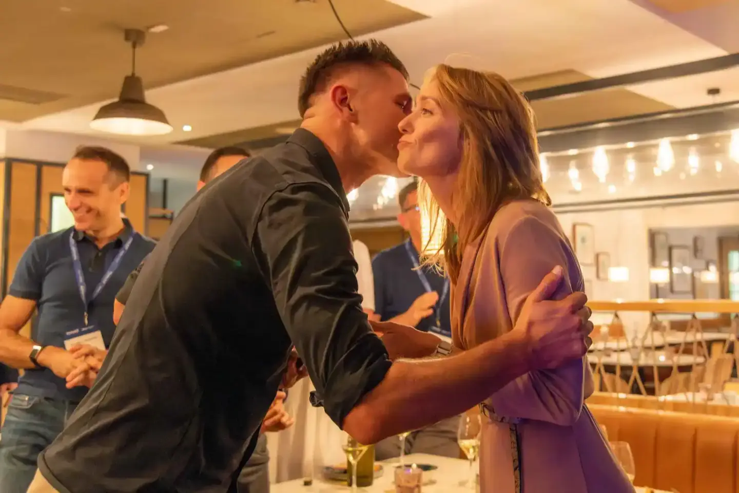 Zwei Personen begrüßen sich herzlich auf einem Firmenevent in Wien, im Hintergrund weitere Gäste und moderne Eventlocation