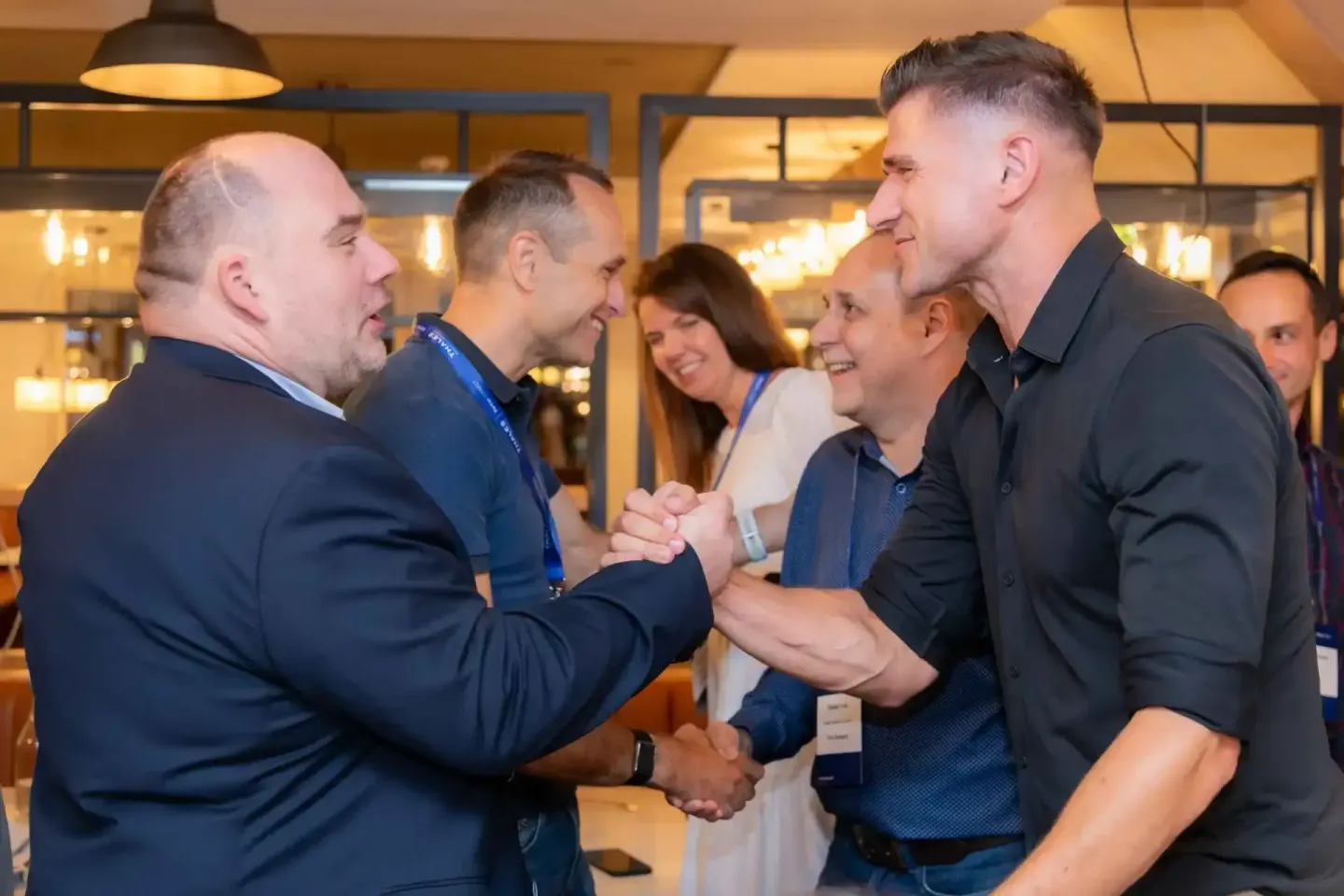 Geschäftsmänner und Geschäftsfrauen beim Networking auf einem Firmenevent in Wien mit Handschlag und lächelnden Gesichtern