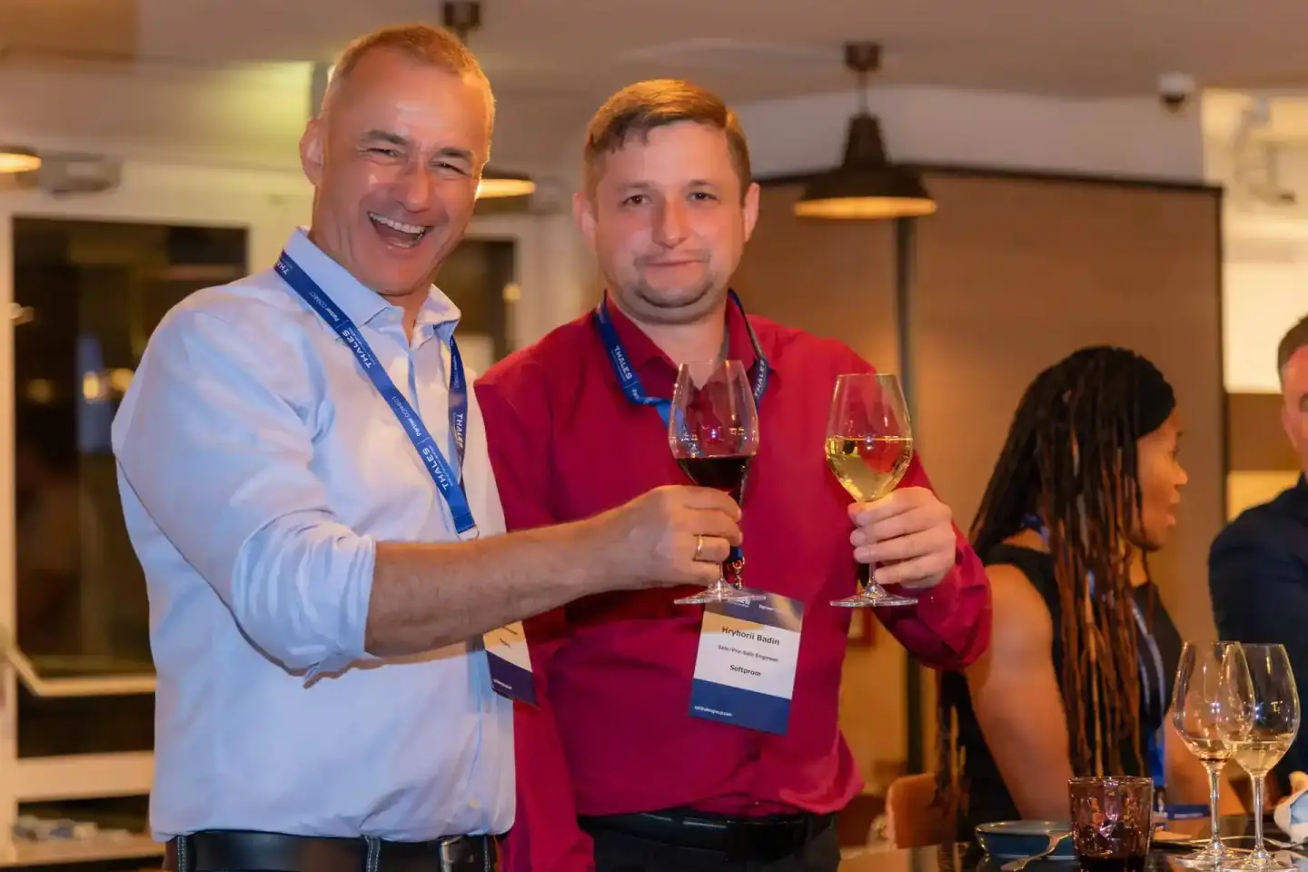 Zwei Männer mit Namensschildern stoßen mit Wein an bei einem Firmenevent Wien