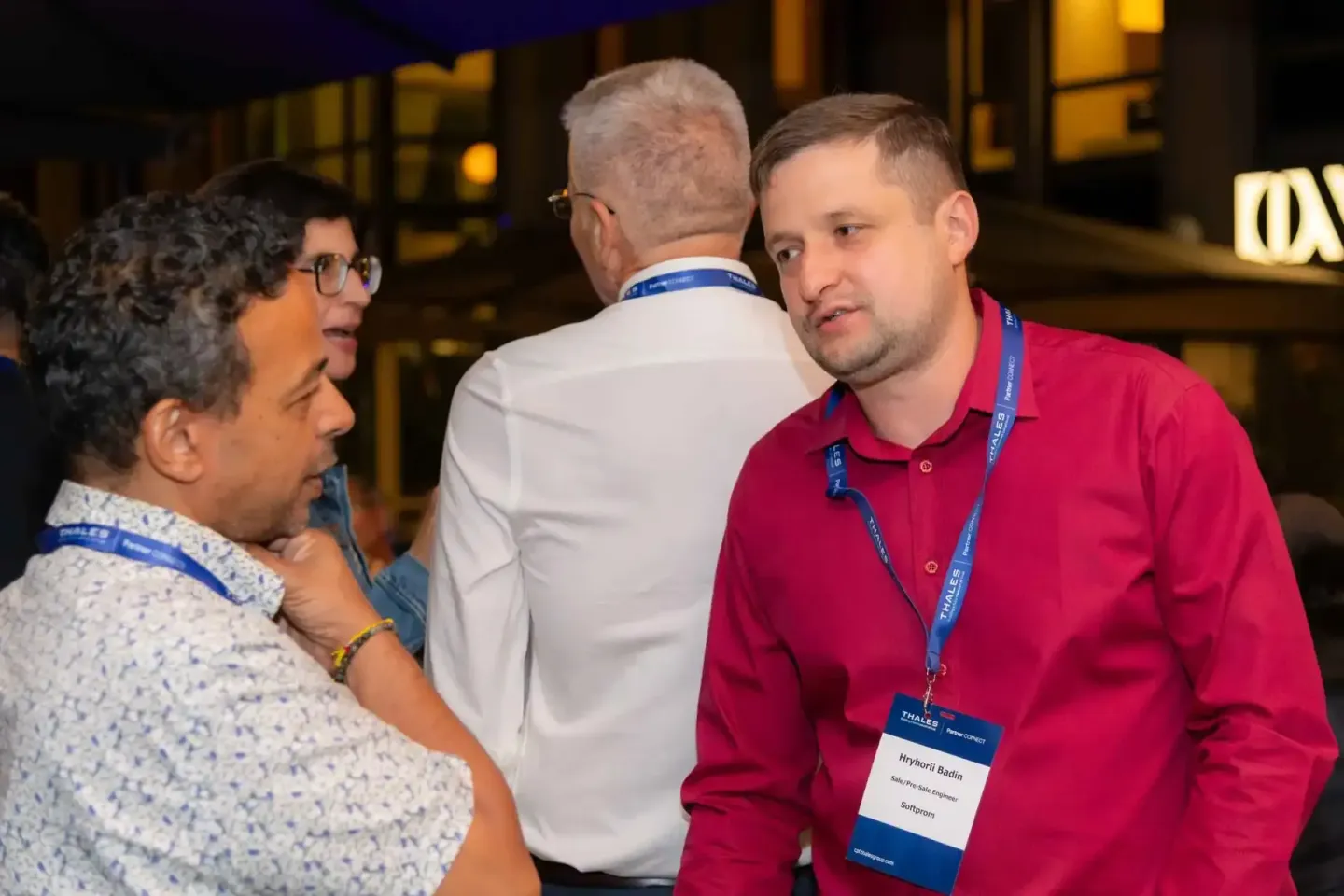 Eventfotograf dokumentiert Networking-Gespräch zwischen drei Personen bei Thales Firmenevent in Wien