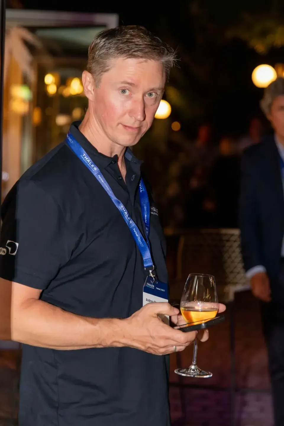 Mann mit Lanyard beim Thales Firmenevent in Wien, hält Weinglas in der Hand, Eventfotografie