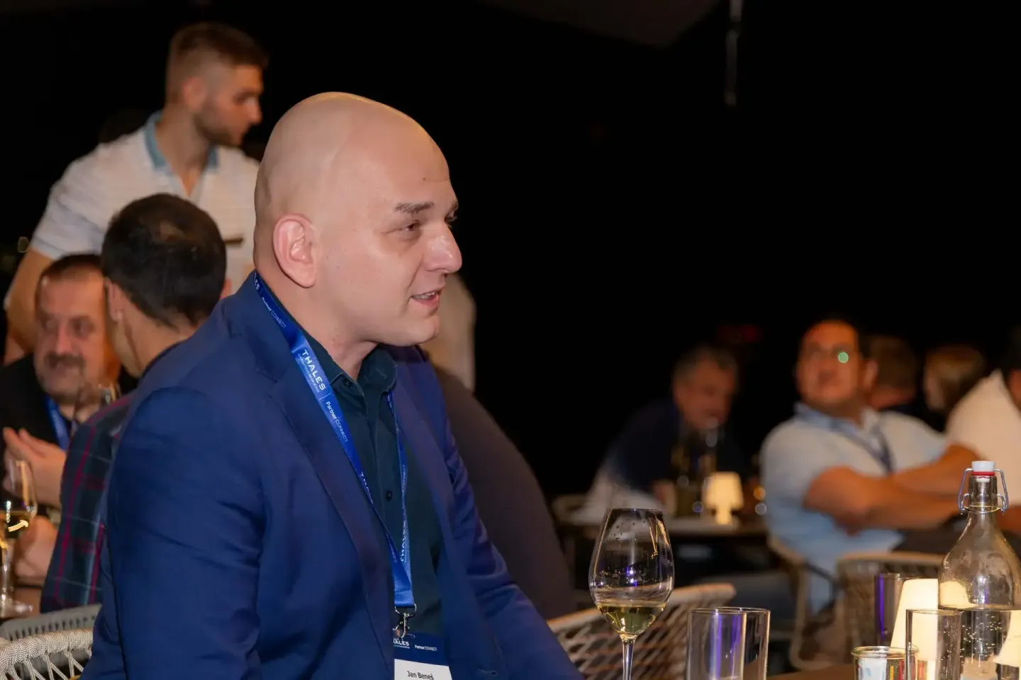 Redner mit blauem Namensschild spricht bei Thales Firmenevent in Wien vor Publikum am Tisch