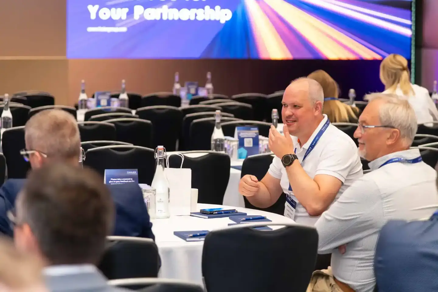 Eventfotograf Wien dokumentiert Geschäftsleute beim Thales-Firmenevent in Diskussionsrunde an Konferenztisch