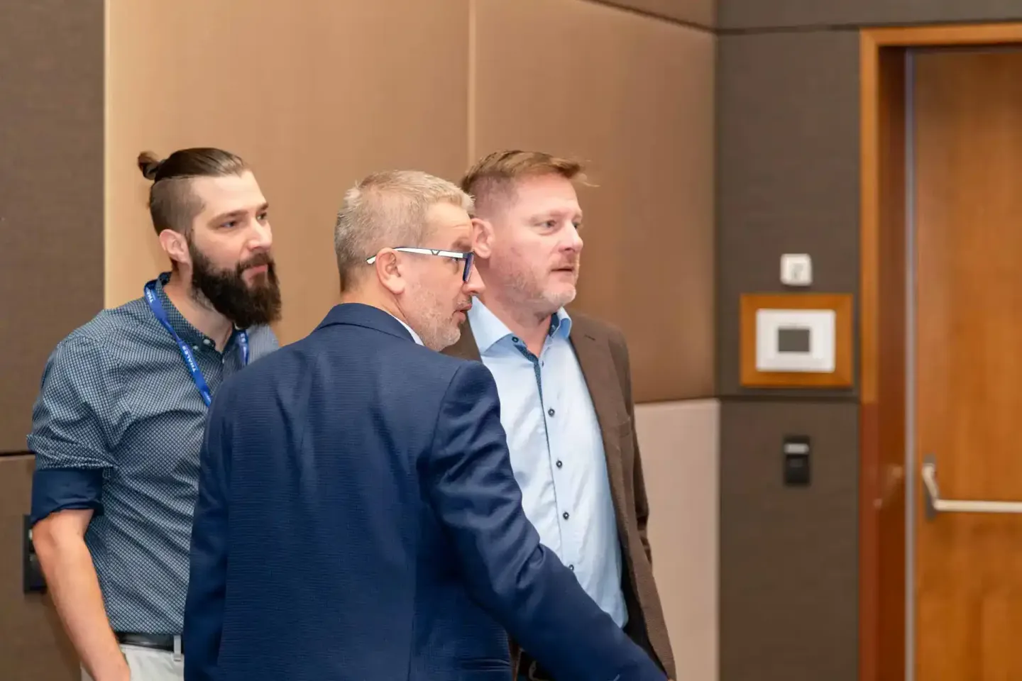 Drei Geschäftsmänner in Business-Kleidung diskutieren auf einem Firmenevent in einem modernen Konferenzraum in Wien