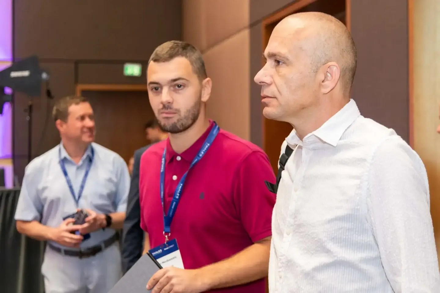Drei Männer bei einer Geschäftsveranstaltung in Wien, einer trägt ein rotes Polo-Shirt mit Namenssschild, Eventfotografie Wie