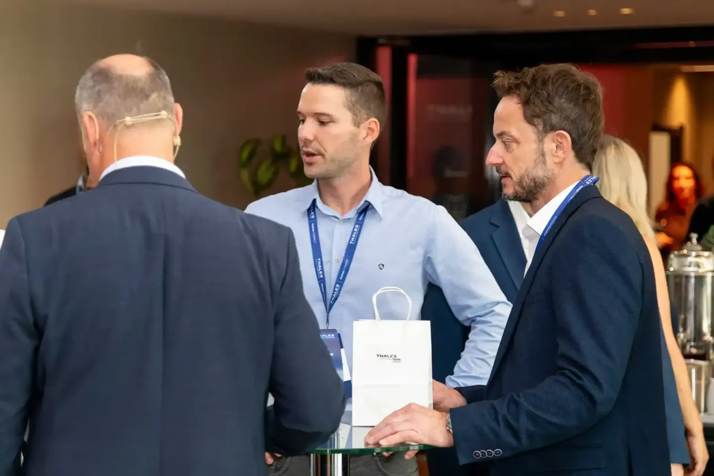 Drei Geschäftsmänner im Gespräch bei einem Thales Firmenevent, Eventfotograf dokumentiert professionelle Networking-Situation