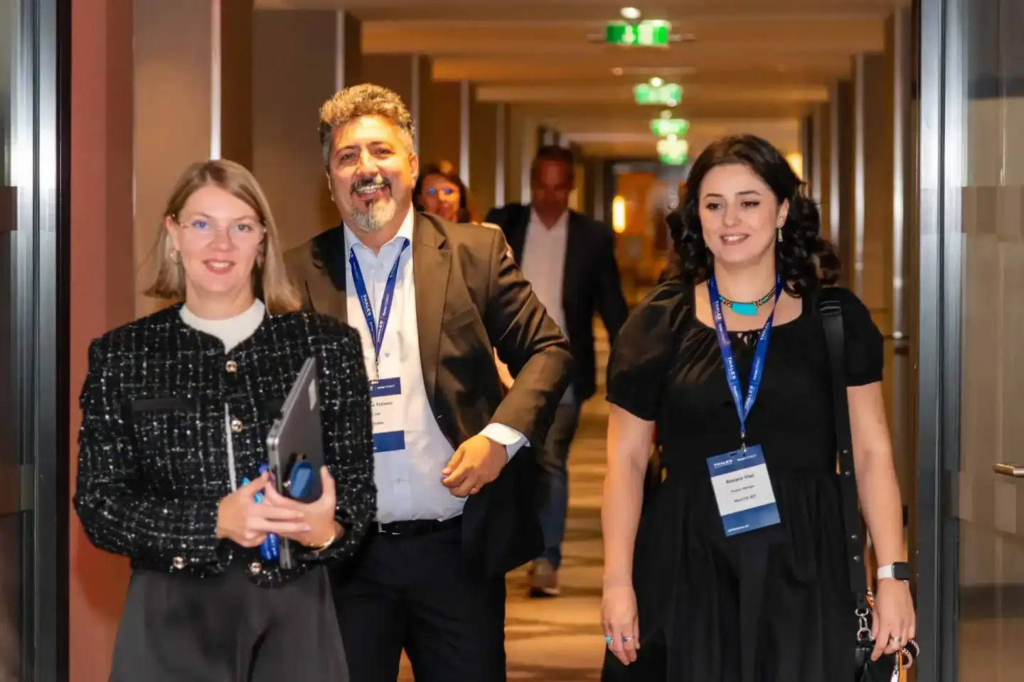 Vier Personen mit Ausweisen in einem modernen Hotelflur während eines Firmenevents Wien, lächelnd zur Kamera