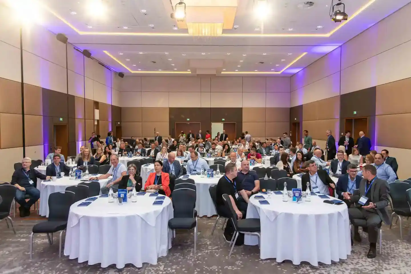 Großes Firmenevent in Wien mit hunderten Gästen an Tischen in modernem Konferenzsaal mit lila Beleuchtung
