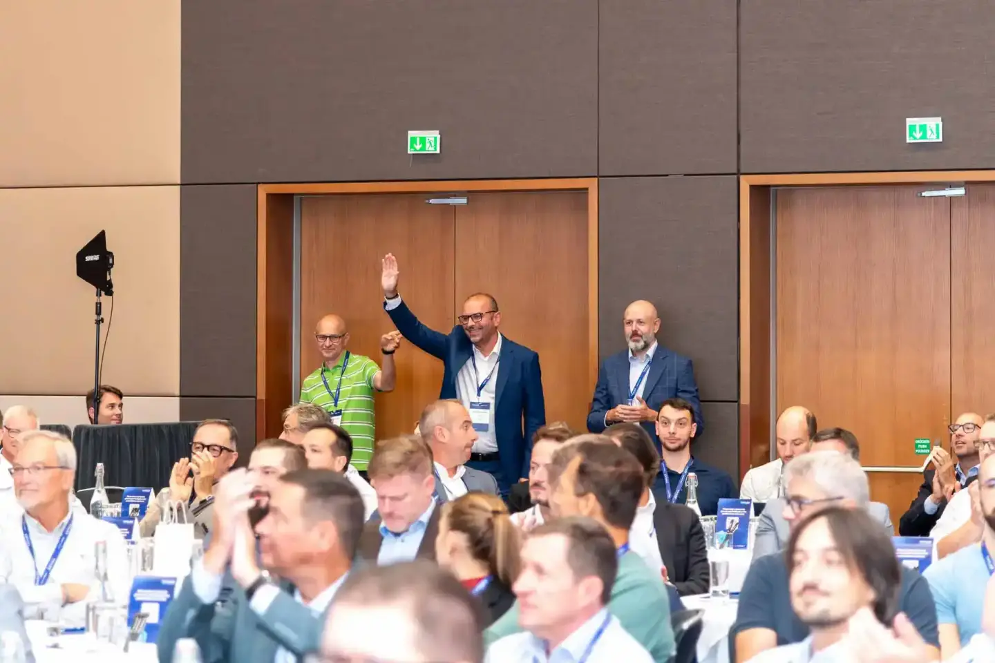 Eventfotografie Wien: Geschäftsmann mit erhobener Hand bei Thales Firmenevent, Publikum und Redner im Konferenzsaal