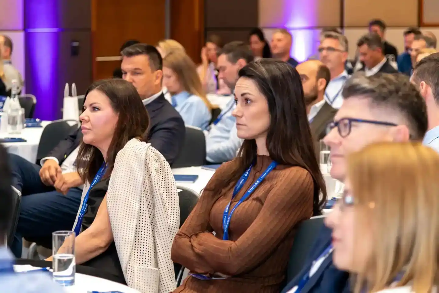 Teilnehmer bei einer Geschäftskonferenz sitzen an Tischen und folgen aufmerksam einer Präsentation - Eventfotografie Wien
