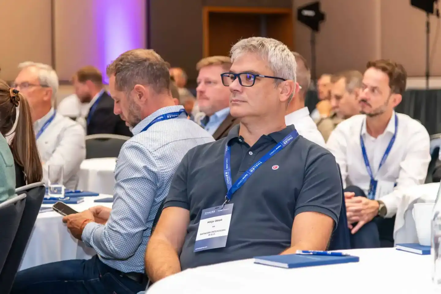 Teilnehmer bei Thales Firmenevent Wien sitzen an Konferenztischen und verfolgen konzentriert eine Veranstaltung