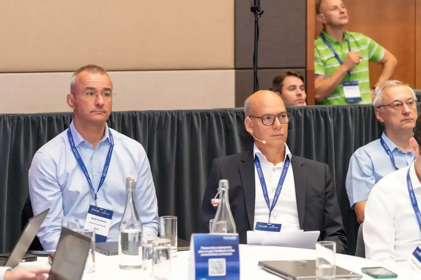 Professionelle Eventfotografie Wien: Paneldiskussion mit drei Geschäftsmännern in Anzügen und Namensschildern an einem Konfer