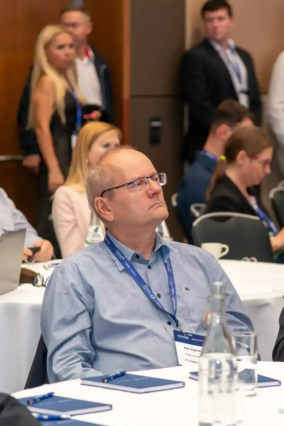 Teilnehmer eines Thales-Events in Wien sitzt konzentriert am Konferenztisch, im Hintergrund weitere Gäste - professionelle Ev