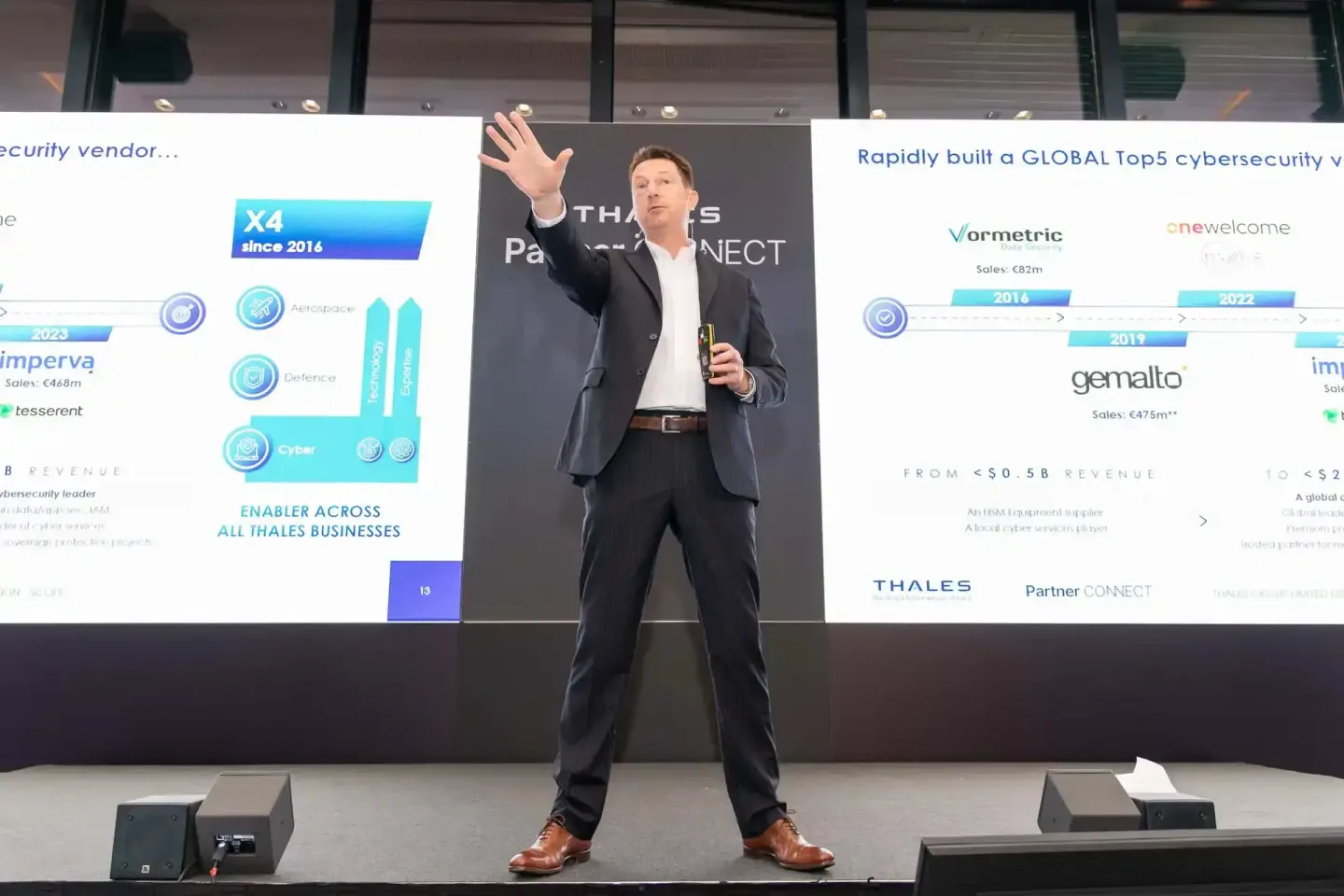 Geschäftsmann präsentiert auf einer Thales-Veranstaltung vor großem Display mit Cybersecurity-Inhalten, professionelle Eventf
