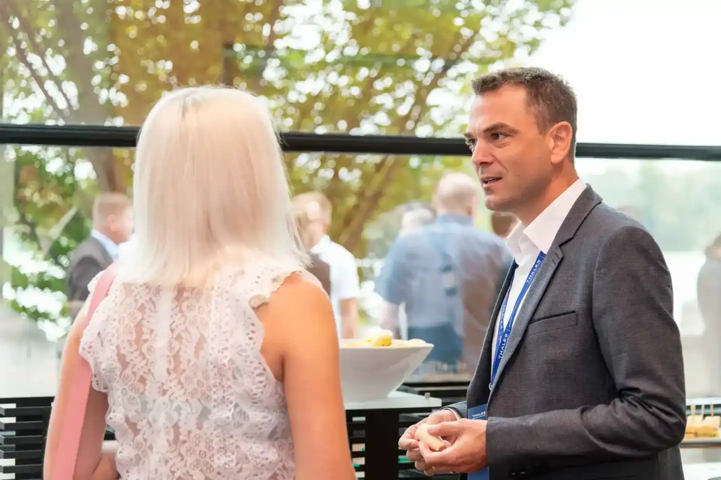 Eventfotograf dokumentiert Gespräch zwischen zwei Personen auf Thales Veranstaltung in Wien mit grünem Garten im Hintergrund