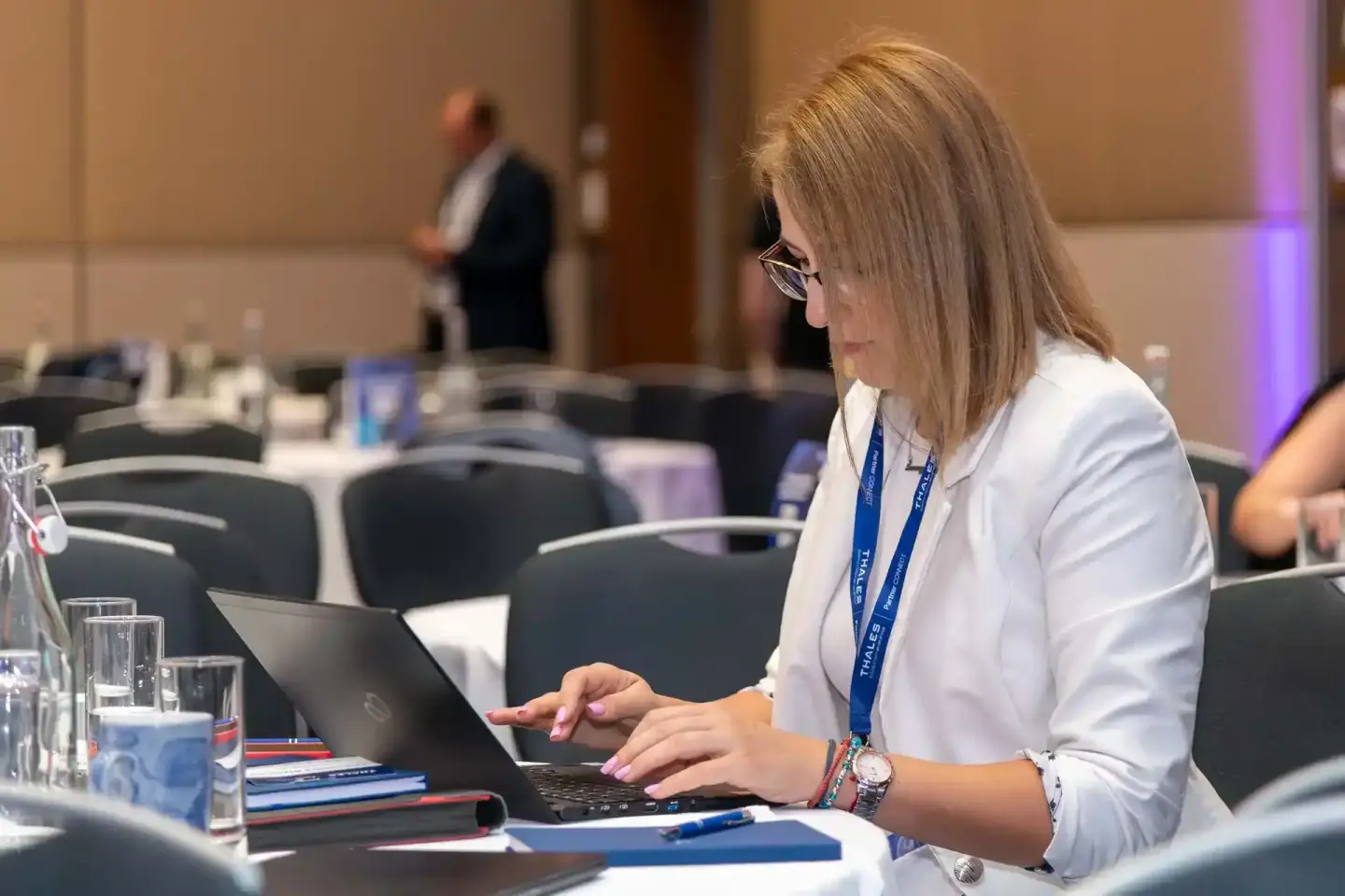 Eventfotograf Wien dokumentiert Geschäftsfrau mit Laptop während Thales-Firmenevent in Konferenzraum