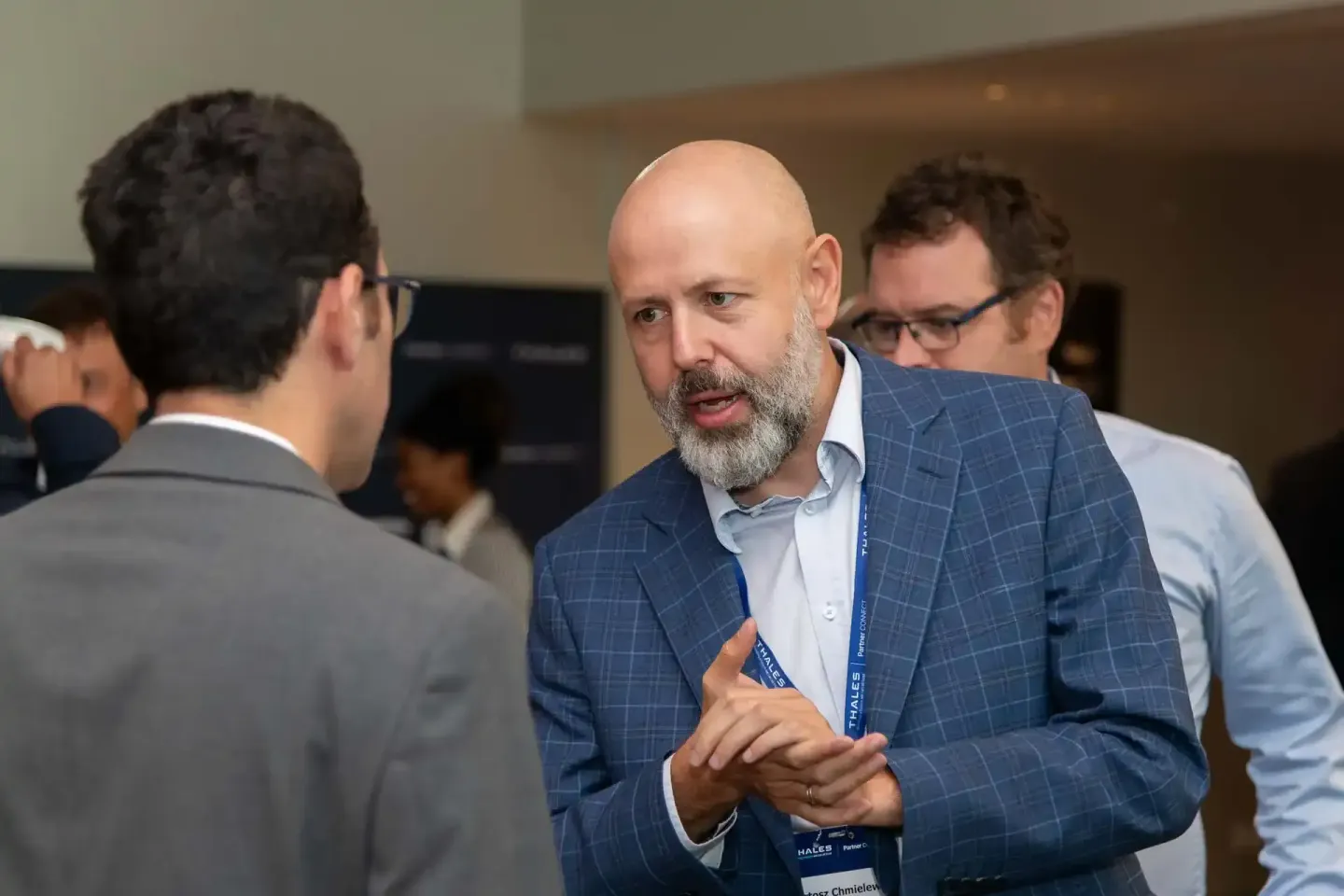 Eventfotograf dokumentiert intensive Geschäftsdiskussion zwischen drei Männern auf Thales-Veranstaltung in Wien