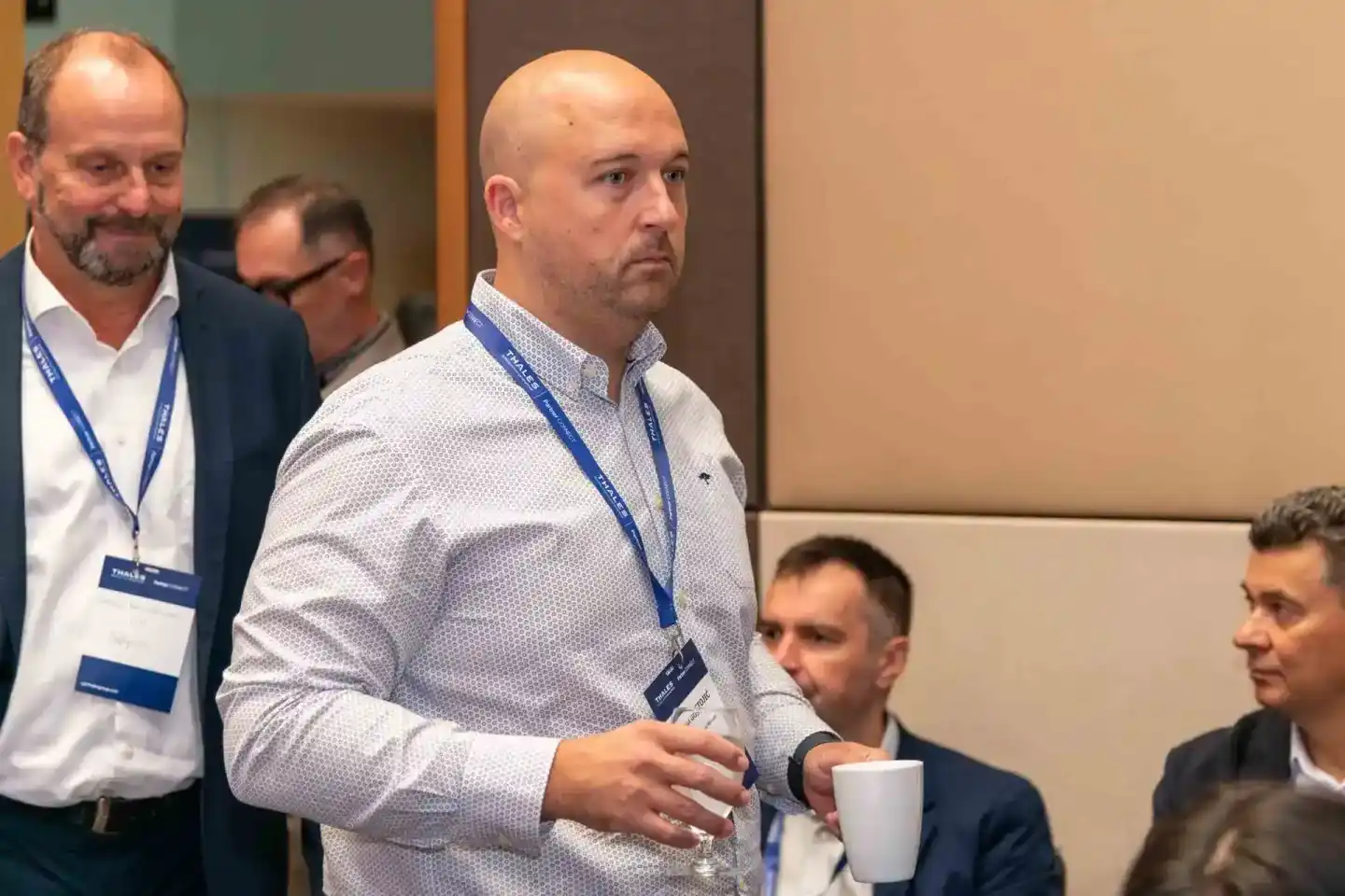 Eventfotograf Wien dokumentiert Geschäftsmann in hellblauem Hemd mit Getränk auf Thales Firmenevent