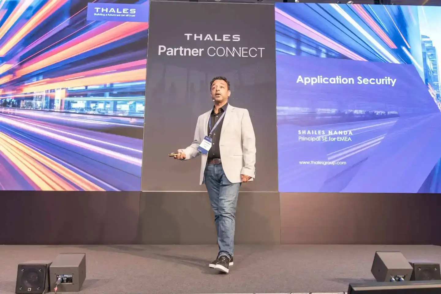 Speaker präsentiert bei Thales Partner Connect Konferenz zum Thema Application Security auf Bühne mit digitaler Kulisse