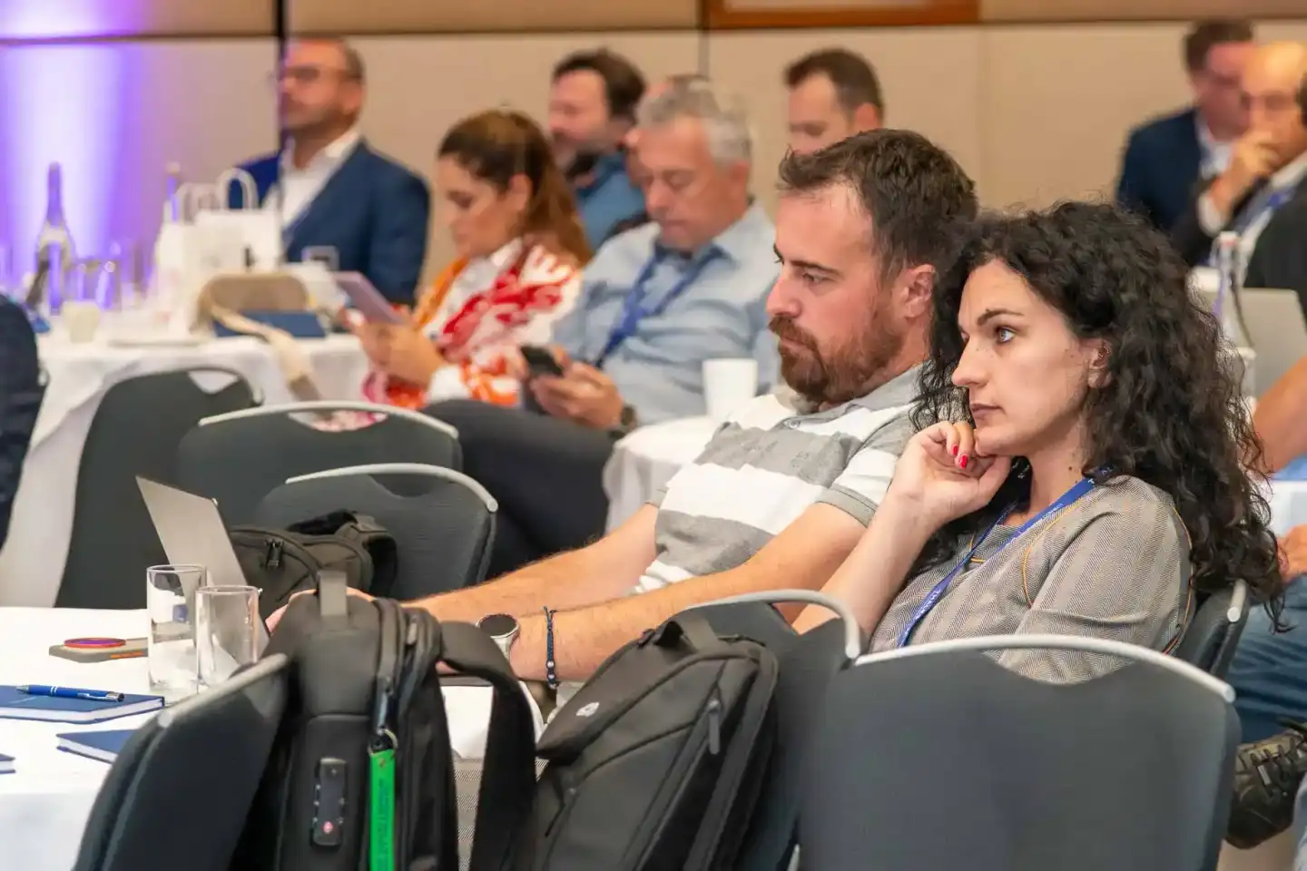 Teilnehmer bei einem Firmenevent in Wien sitzen an Konferenztischen und folgen konzentriert einer Präsentation