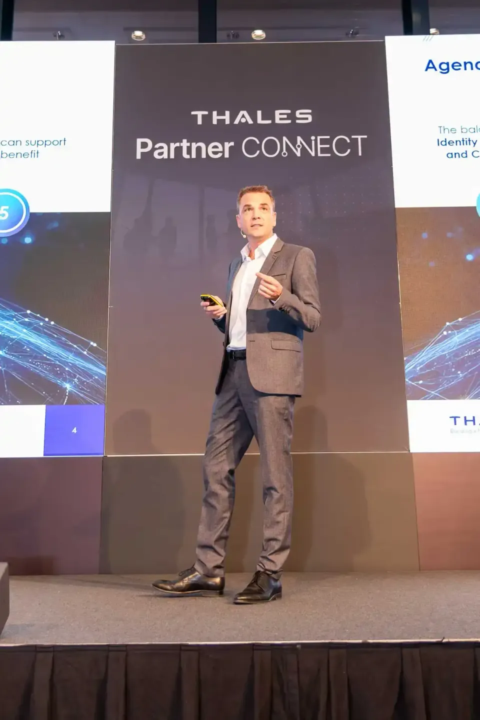 Geschäftsmann präsentiert auf der Bühne vor Thales Partner Connect Backdrop - Eventfotografie Wien