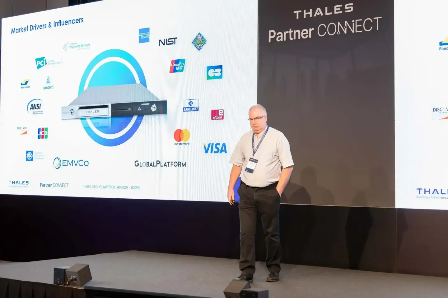 Eventfotograf präsentiert bei Thales Partner Connect Konferenz auf großer Bühne mit Marktdriver-Logos