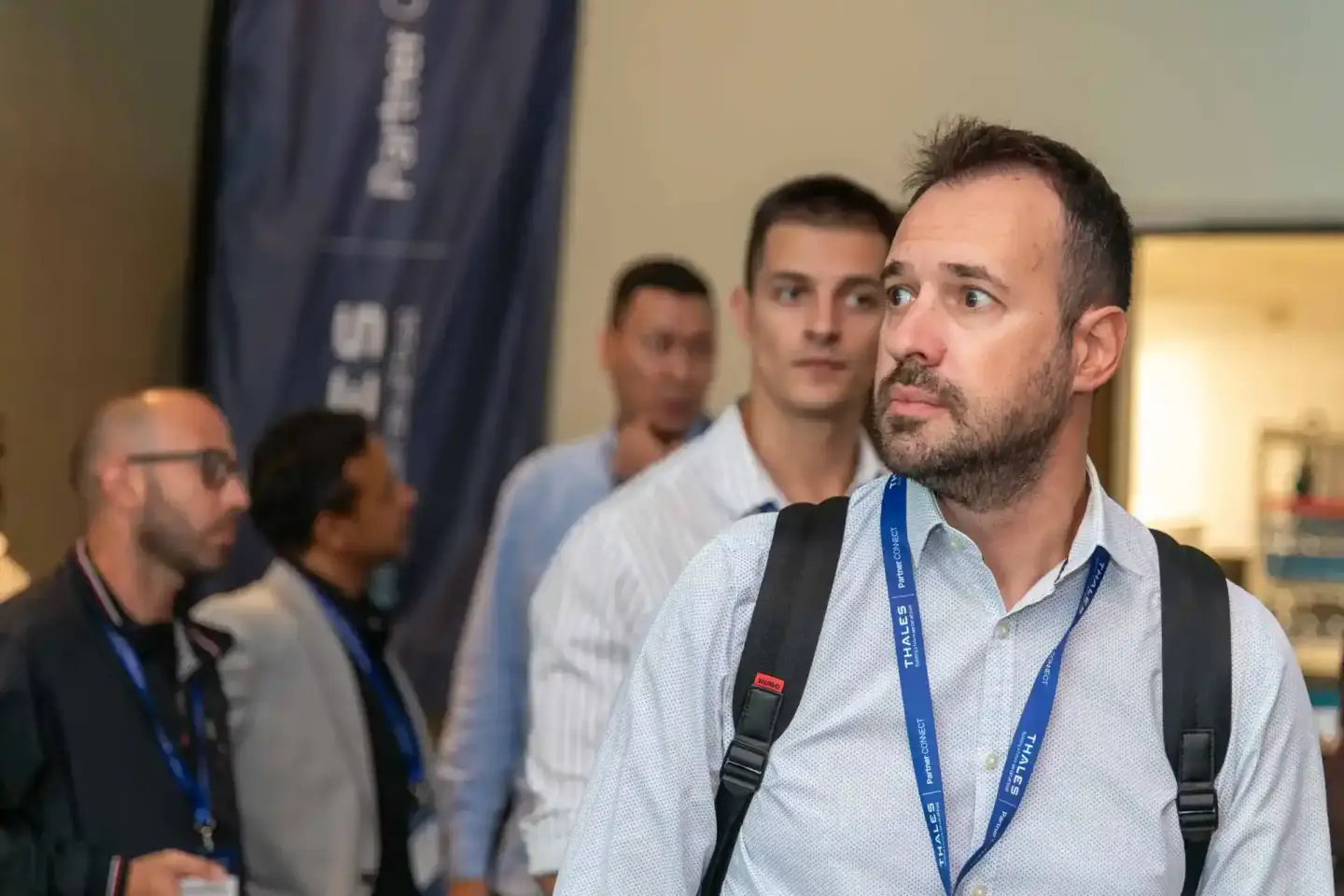 Eventfotografie Wien: Mann mit blauem Lanyard bei Thales Firmenevent, im Hintergrund weitere Teilnehmer