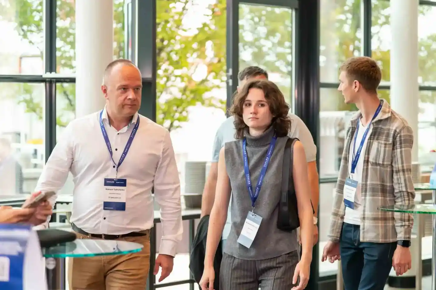Drei Teilnehmer mit Ausweisen beim Thales Firmenevent Wien in modernem Büro mit Panoramafenstern
